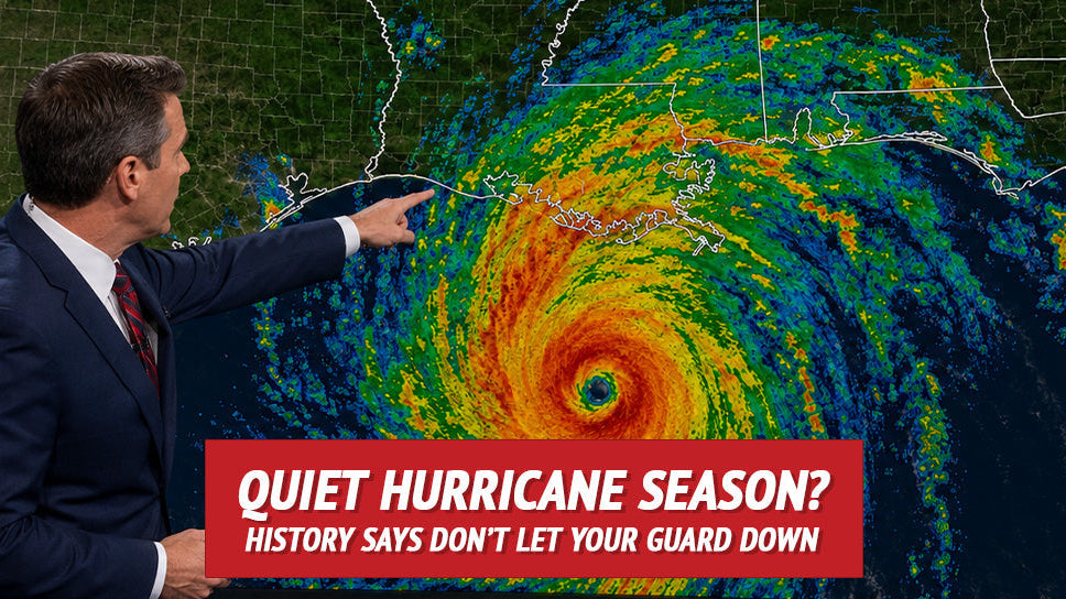 A weather presenter points toward a large hurricane map graphic on a studio screen. A red banner at the bottom reads 'Quiet Hurricane Season? History Says Don't Let Your Guard Down.