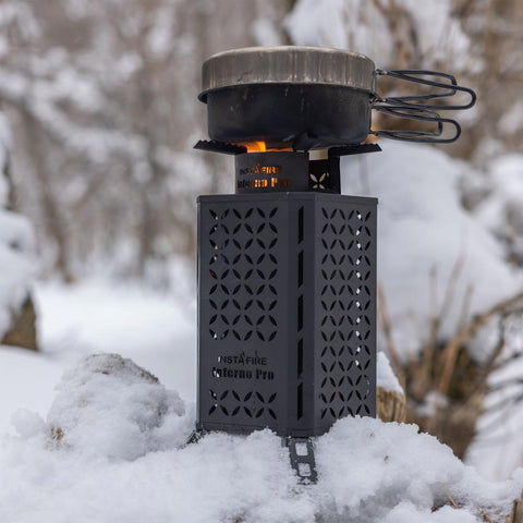 Image of The Inferno Pro sitting on a pile of snow, with a cooking pan placed above the flame.