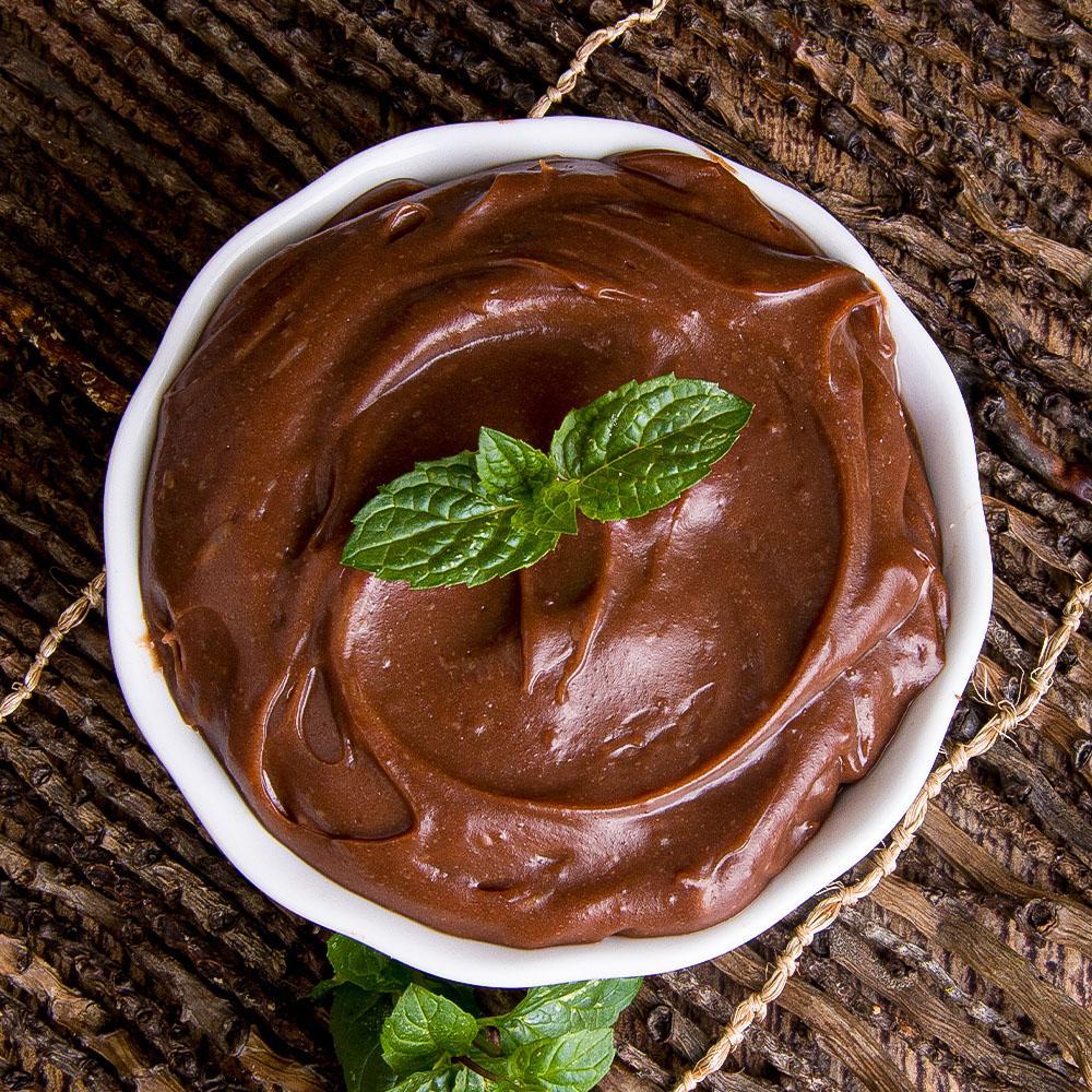 Overhead view of chocolate pudding in a white bowl, garnished with a mint leaf.