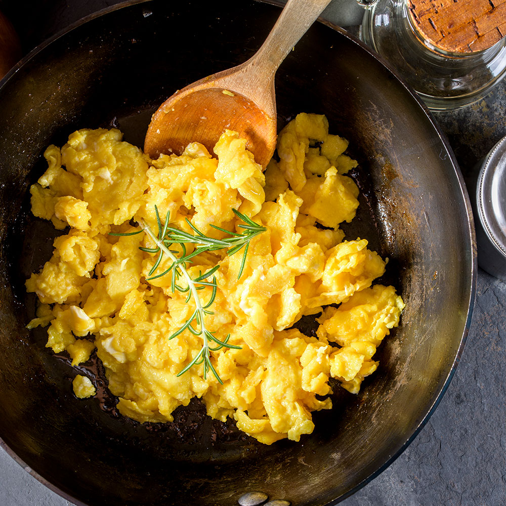 Scrambled Eggs in a cast iron pot with thyme as garnish.