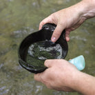 Hand in a stream using a washing a dish wiht readsy hour camp soap