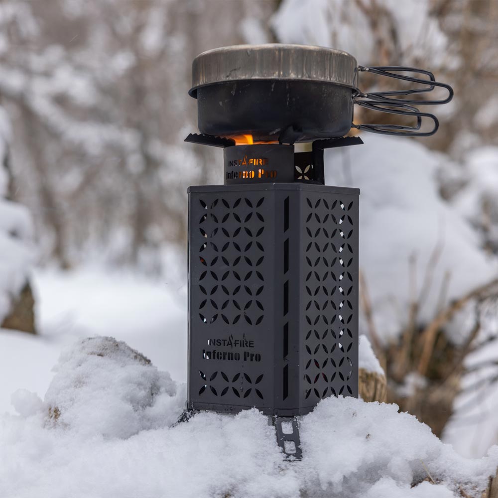 The Inferno Pro sitting on a pile of snow, with a cooking pan placed above the flame.