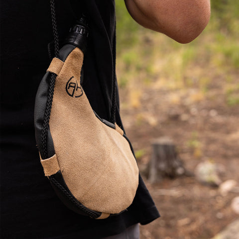 Image of Man wearing a tan leather bota bag on his side outdoors.