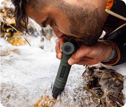 Man using the Survival Straw Personal Water Filter to drink from a stream