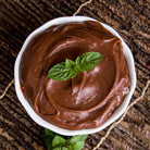 Overhead view of chocolate pudding in a white bowl, garnished with a mint leaf.