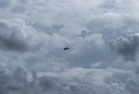 A small airplane on its own across a blue sky.