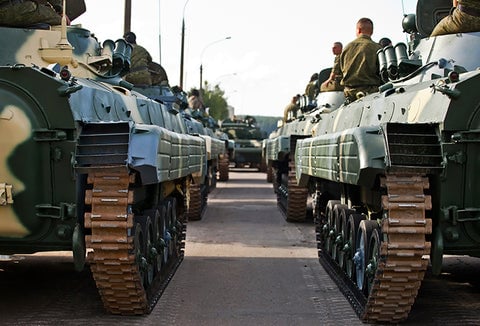 Russian soldiers lined up on military tanks, heading to war.