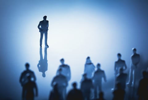 A person in gray facing a whole group of people wearing gray.