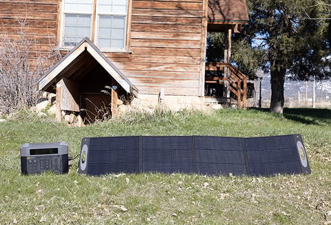 A Grid Doctor solar generator and solar panel set up in a backyard.
