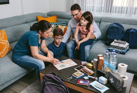 A family in a living room sitting together around a coffee table, planning for emergencies together.