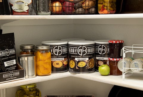 Cans of food stored on a pantry shelf.