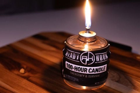 A lit Ready Hour 100-Hour Candle on a wood table indoors.