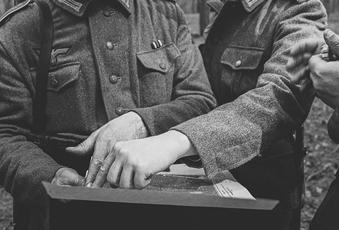 WWII soldiers planning a battle strategy on paper.