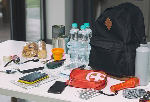 A bunch of different survival supplies spread out on a white countertop.
