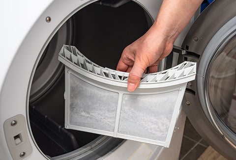 A person removing dryer lint from a dryer.