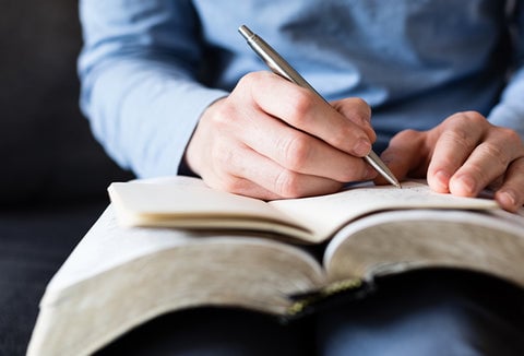 Woman studying a book and taking notes.