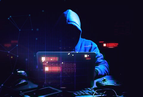 A hooded hacker using a computer to break into systems.