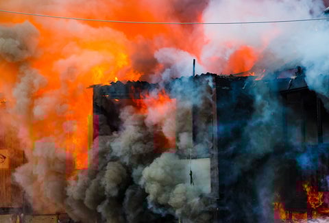 A building on fire, surrounded by smoke.