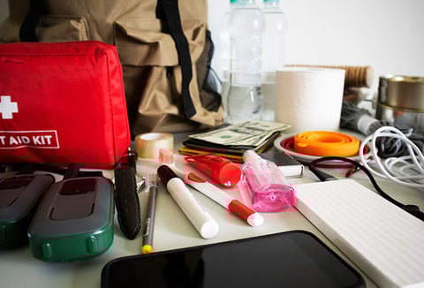 A bunch of loose supplies for an emergency kit spread out on a table.