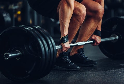 A man crouching to lift up some weights at the gym.