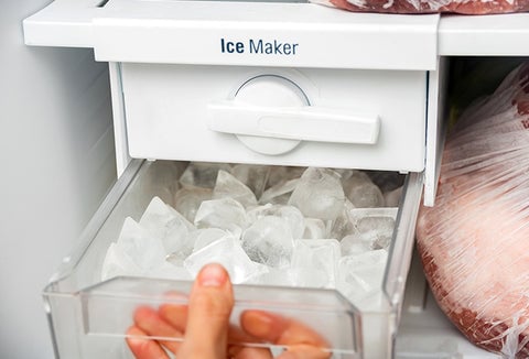 A person pulling out an ice maker from their freezer.