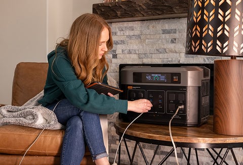 A woman in her living room plugging a tablet into the Grid Doctor 3300 Solar Generator.