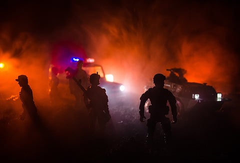 A police car and police officers navigating through fire and smoke.