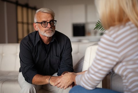 A man and woman seated on a couch, having a serious conversation.