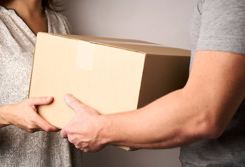 A woman handing off an unmarked cardboard box to a man.