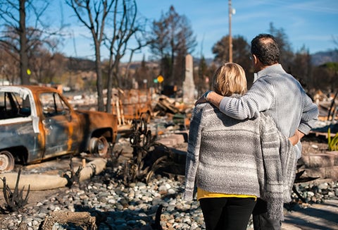 A couple looking out at their property that's been destroyed by natural disaster.
