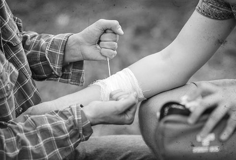Administering first aid in the wilderness, pictured in black and white.
