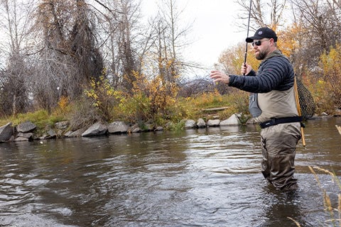 A man standing in a river and fishing.