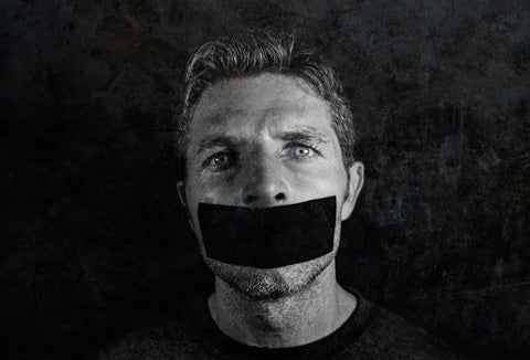 A man's face wearing a piece of tape over his mouth