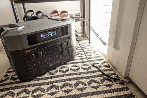 A Grid Doctor generator plugged in and sitting on a rug indoors.