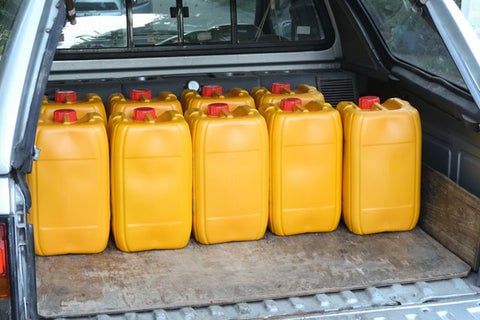 Yellow jugs of fuel stored neatly in the back of a vehicle.