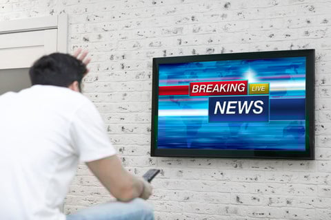 Someone watching a breaking news report on TV.